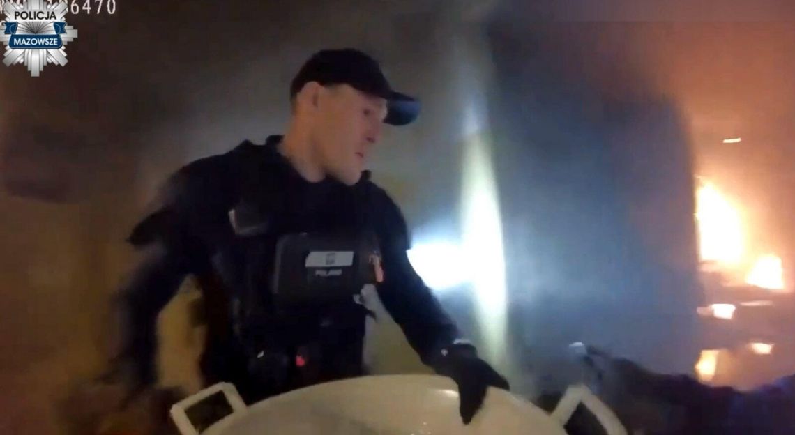 Policjanci wchodzą do płonącego mieszkania i wyciągają z niego dwie osoby. Wideo z kamery na mundurze